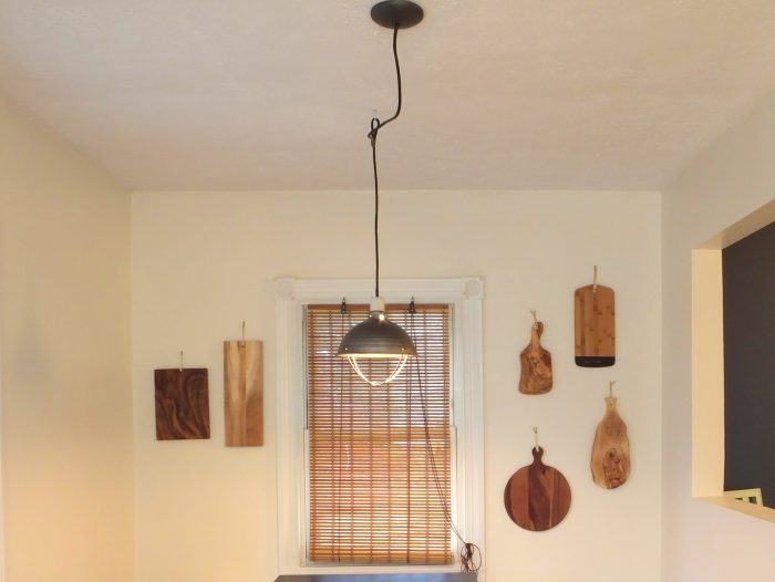 A dark industrial lamp hanging in front of window