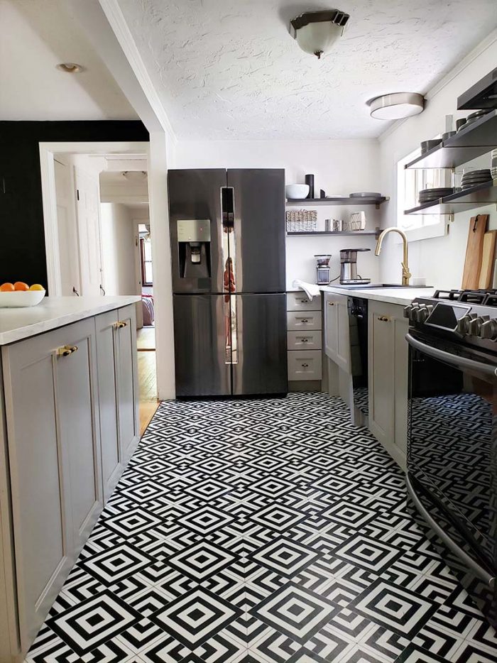 remodeled galley kitchen with gray cabinets, black appliances and geometric black and white tile floor